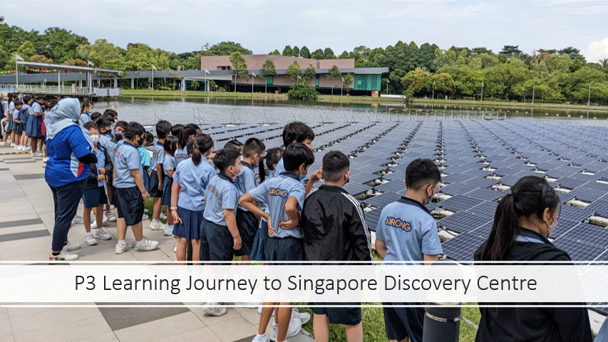 Students in blue uniforms stand beside a lake covered with floating solar panels at Singapore Discovery Centre.